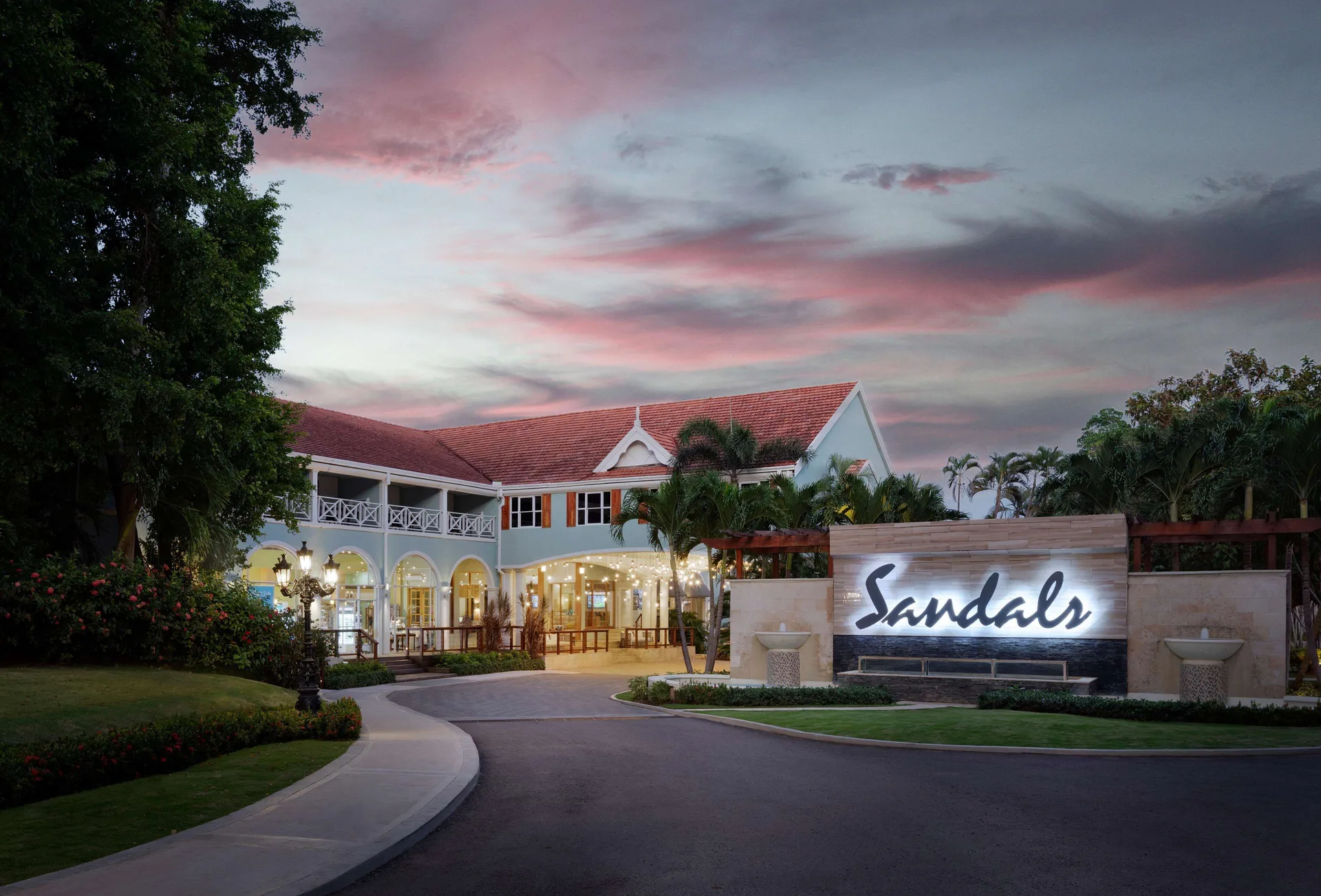 Illuminated entrance sign and resort building at dusk at Sandals Ochi.