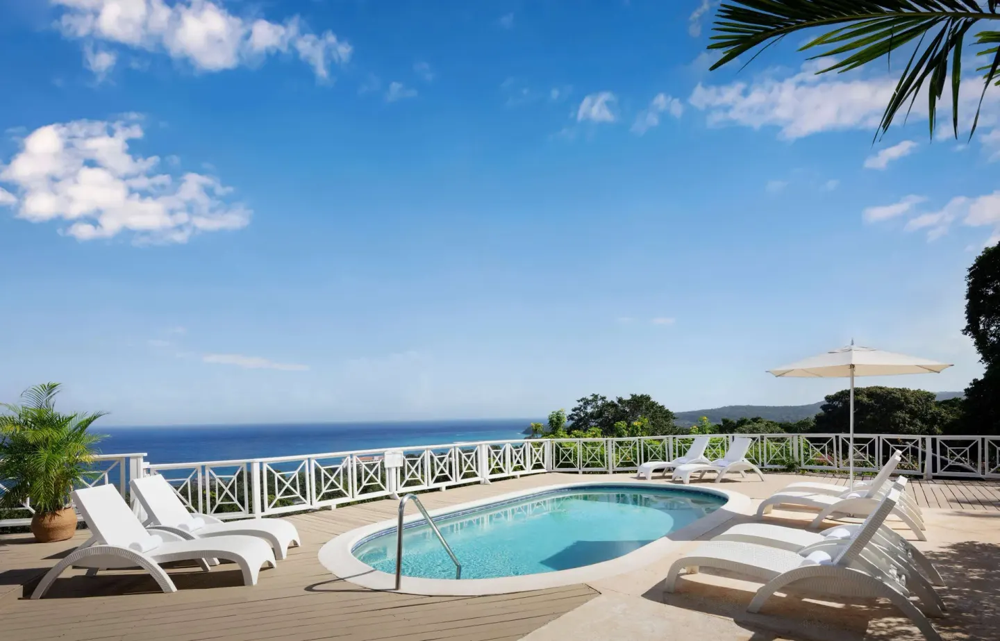 A small pool with white loungers overlooks the blue sea at Sandals Ochi.