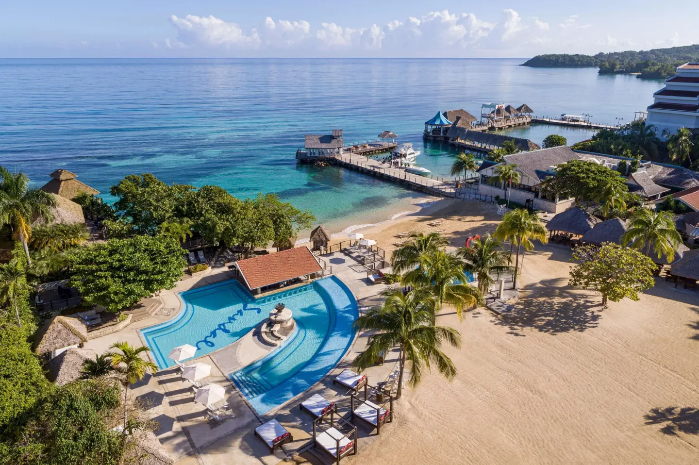 Aerial resort view with pool, beach, piers, and calm sea at Sandals Ochi.