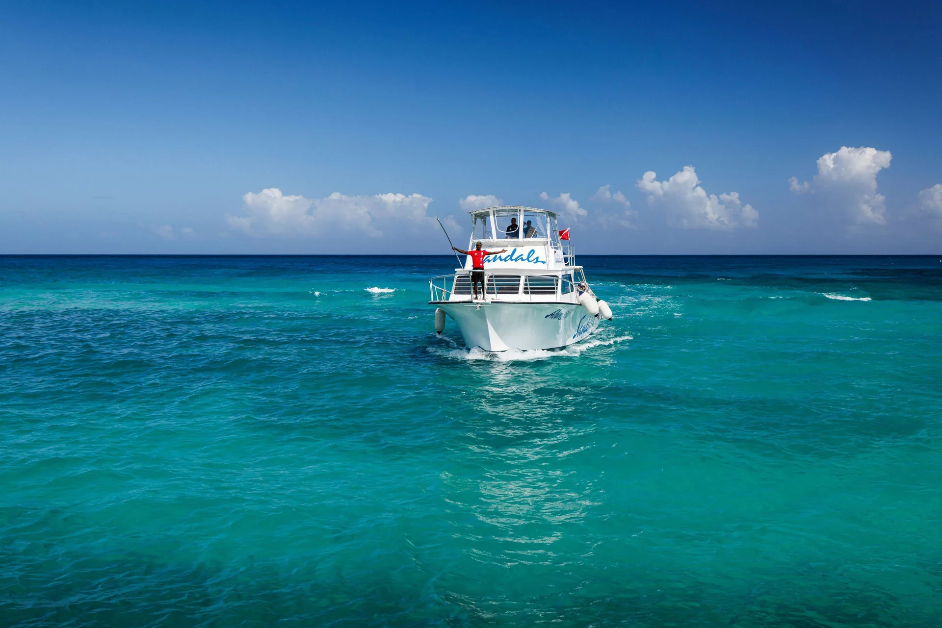 A white resort boat cruises across turquoise water near Sandals Ochi.