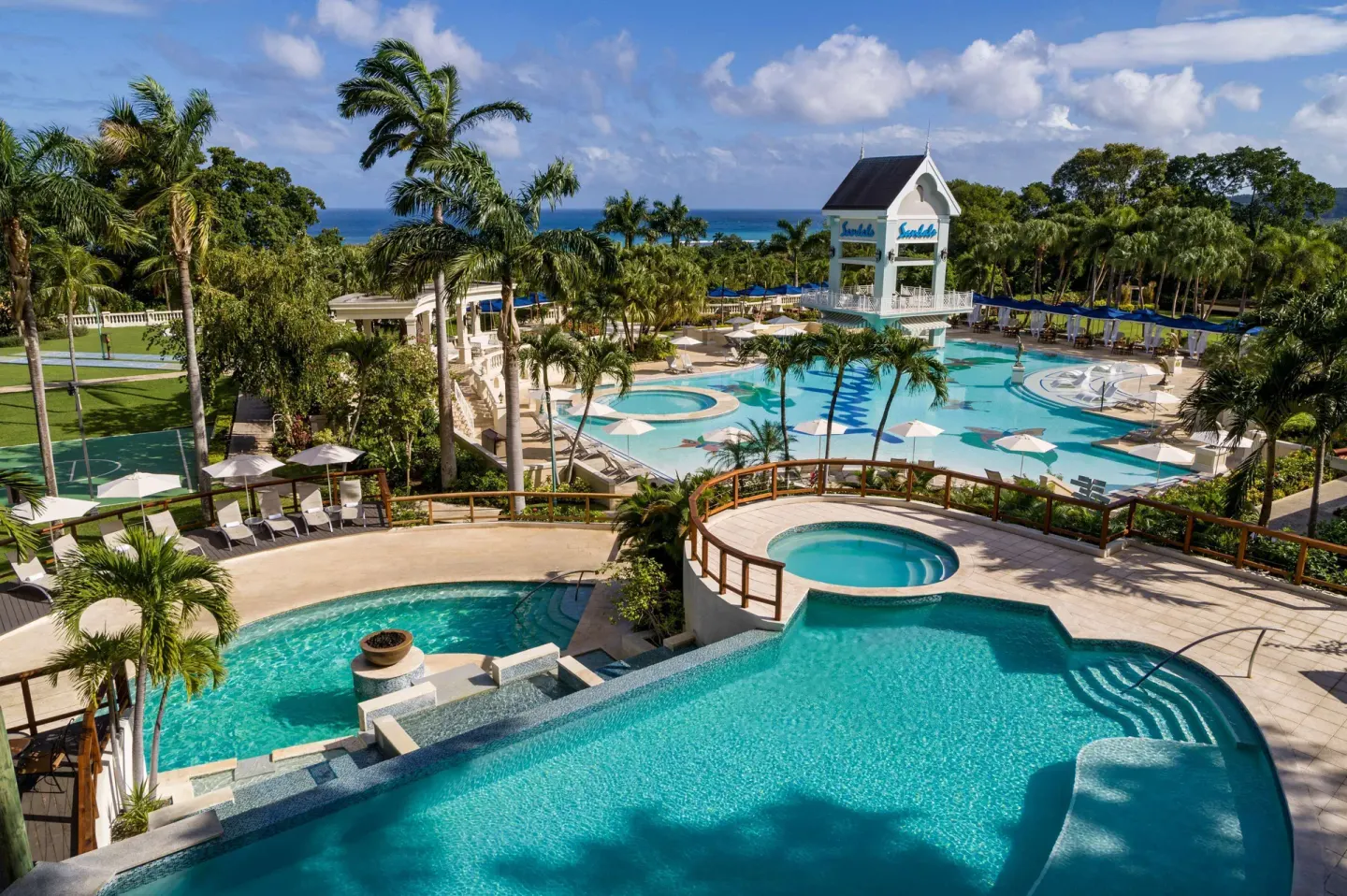 Terraced pools and the main pool with palms and ocean in the distance at Sandals Ochi.