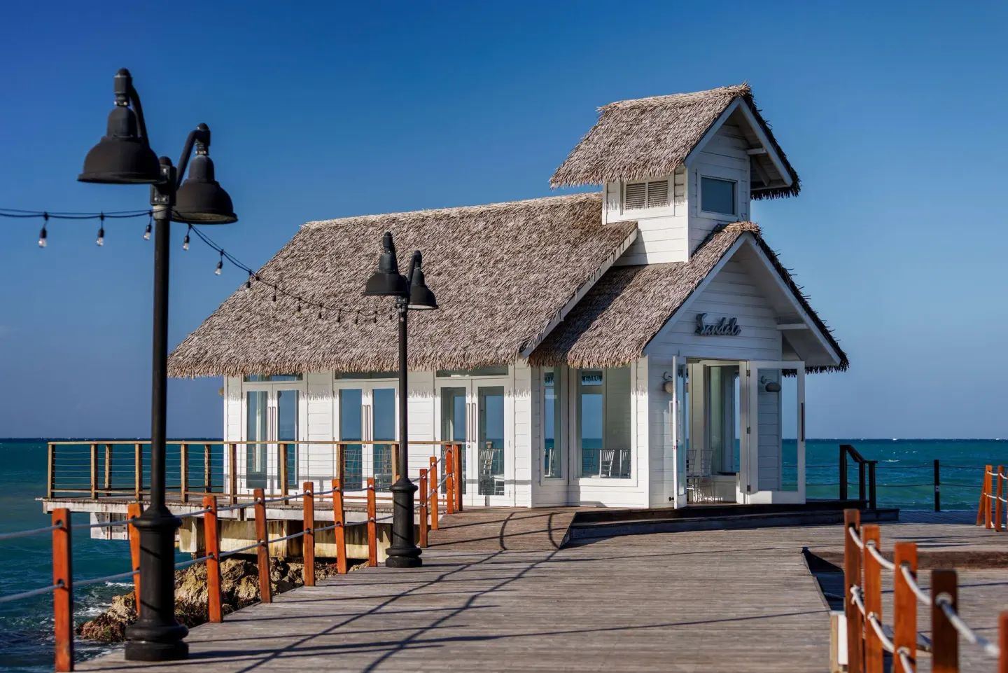 White thatched overwater building on a pier at Sandals Ochi.