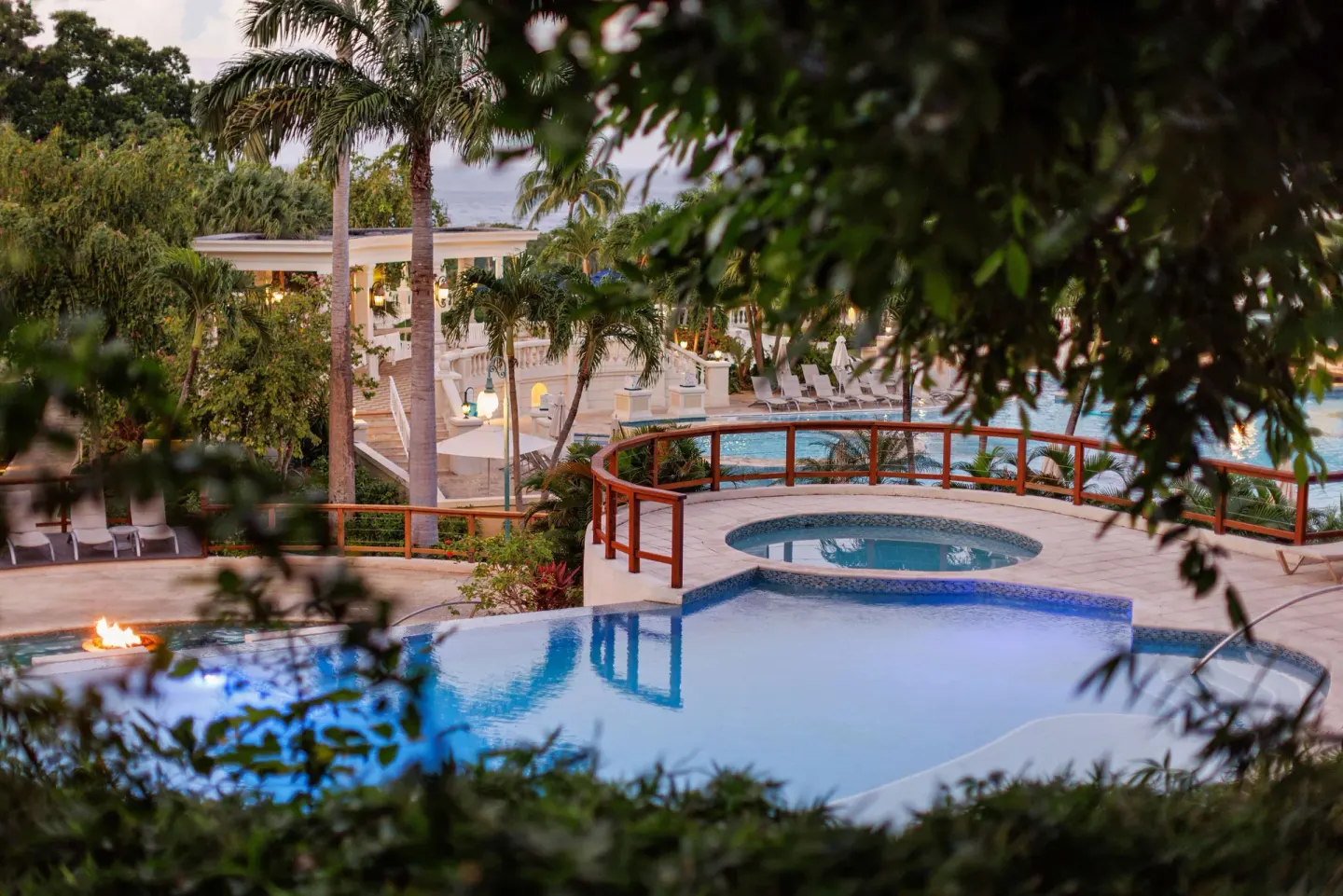 Tiered pools and a hot tub are framed by tropical foliage at Sandals Ochi.