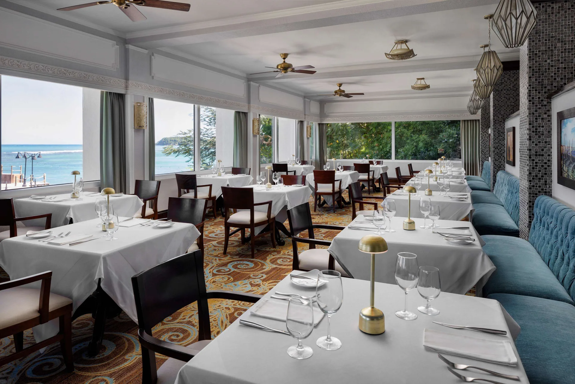 A white-tablecloth dining room with ocean-view windows is set at Sandals Ochi.