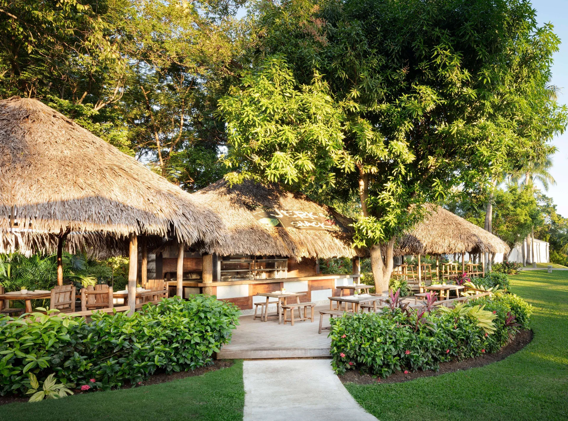 Thatched outdoor café seating surrounded by tropical landscaping at Sandals Ochi.
