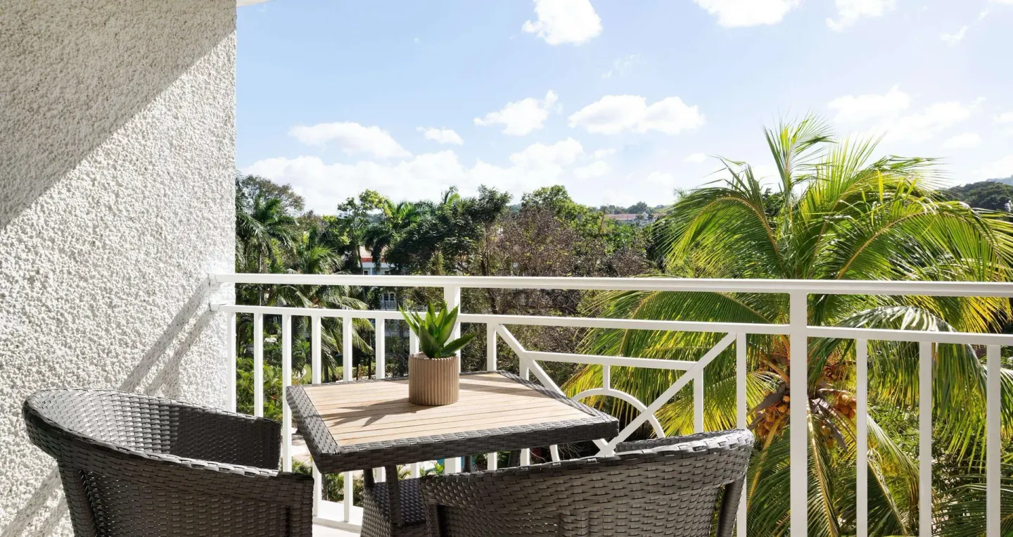Furnished balcony with garden and palm views for a luxury room at Sandals Ochi.