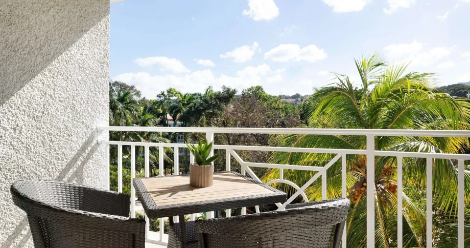 Furnished balcony with garden and palm views for a luxury room at Sandals Ochi.