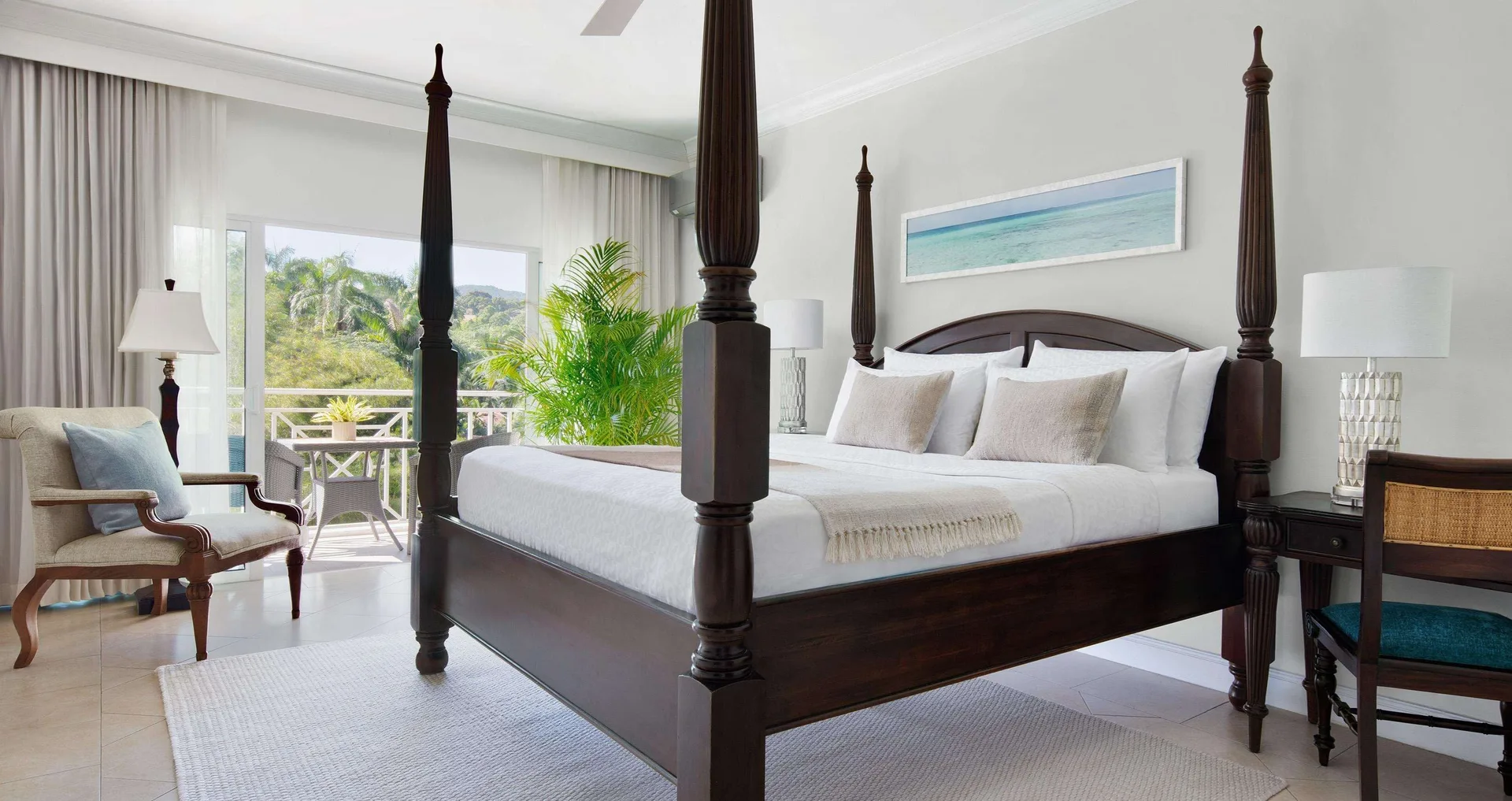 Four-poster king bed in a Luxury Room at Sandals Ochi with balcony doors and garden view beyond.