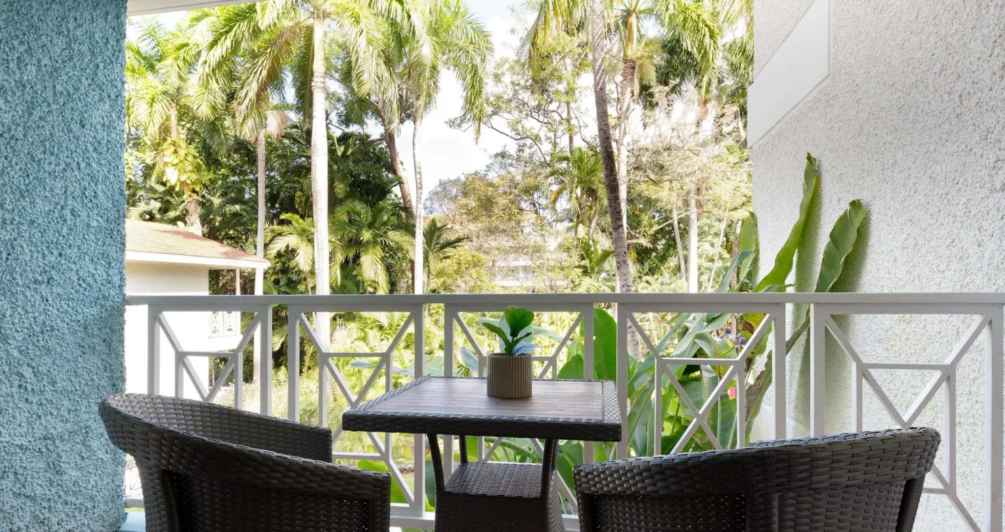 Furnished garden-view balcony for a Premium Room at Sandals Ochi with palms beyond the railing.