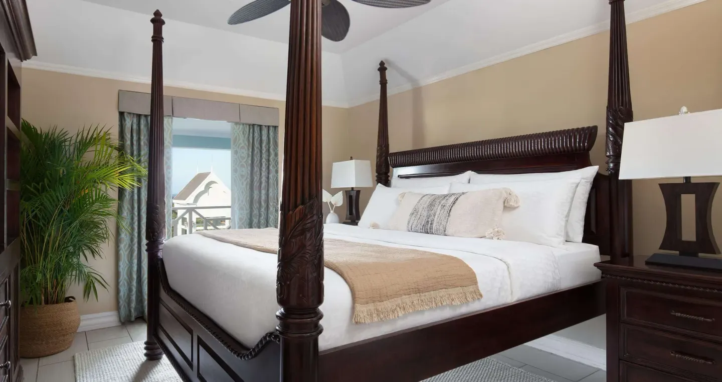 Four-poster king bed in a Great House Oceanview room at Sandals Ochi with balcony beyond.