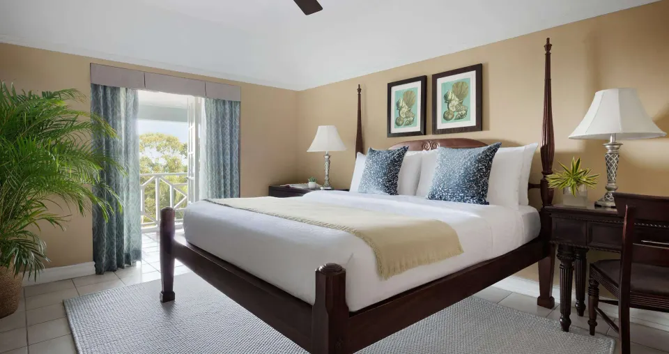 King bed, desk, and balcony doors in a Great House Oceanview room at Sandals Ochi.