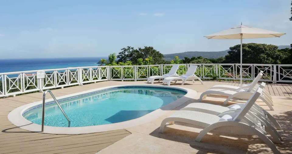Ocean-view pool terrace with white loungers at Sandals Ochi.