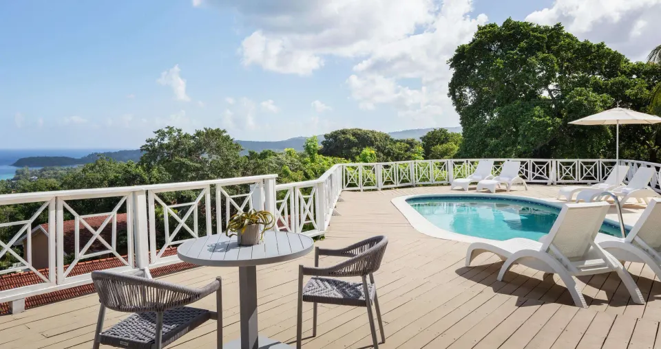 Poolside villa terrace with ocean view and loungers at Sandals Ochi.