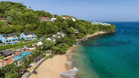 Aerial view of Sandals Regency La Toc with beach, pool, hillside rooms, and turquoise sea.