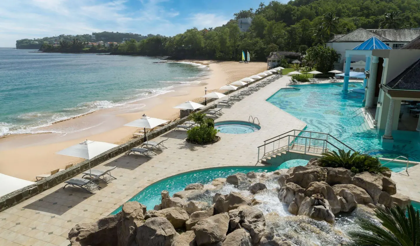 Beachfront pool, whirlpool, umbrellas, and calm bay at Sandals Regency La Toc.