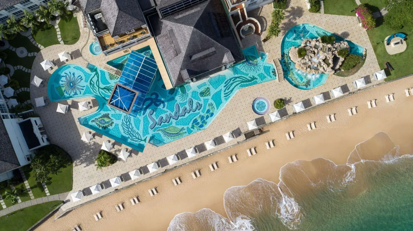 Aerial view of the beachfront pool deck and sandy shore at Sandals Regency La Toc.