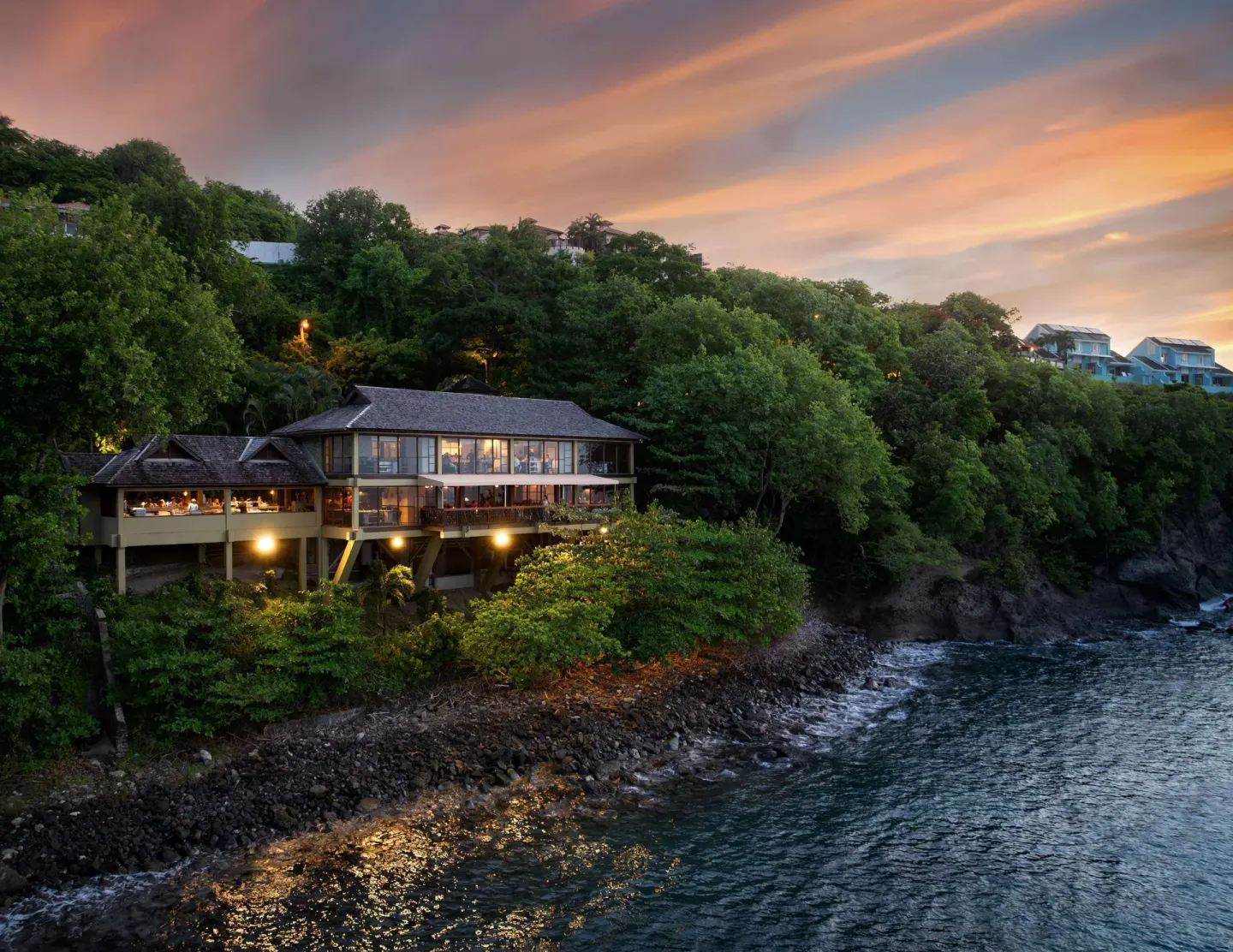 Clifftop building above the rocky shoreline at sunset at Sandals Regency La Toc.