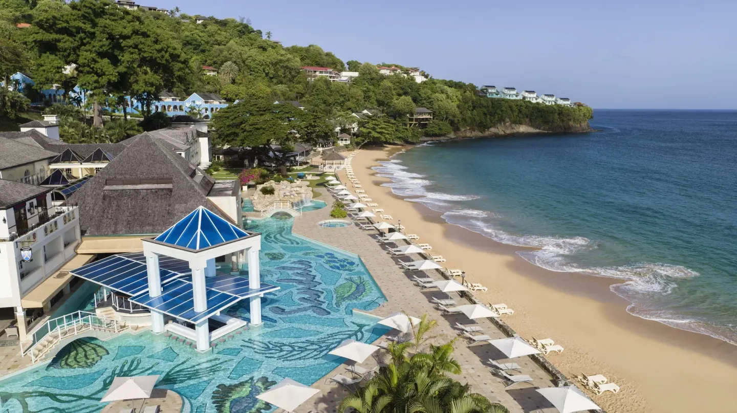 Curving beachfront pool and sandy cove beside the sea at Sandals Regency La Toc.