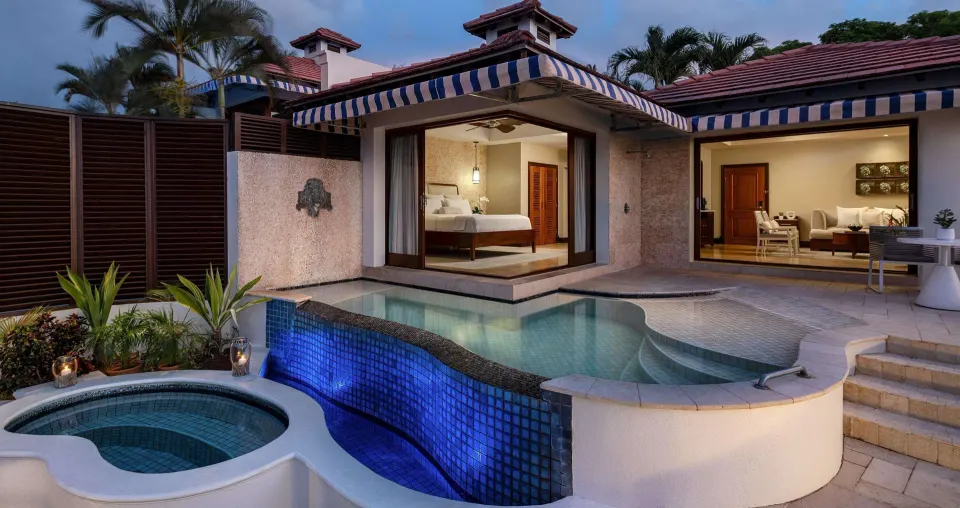 Private villa pool and hot tub outside a lit bedroom at Sandals Regency La Toc.