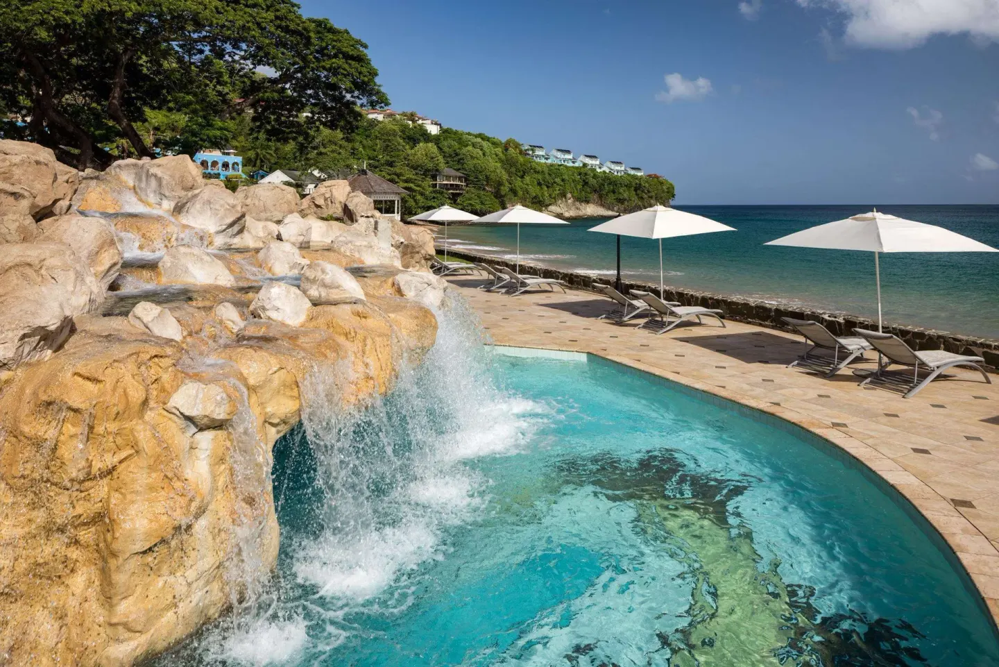 Rock waterfall spilling into a pool beside the beach at Sandals Regency La Toc.