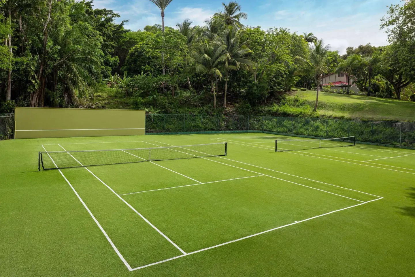 Green tennis courts sit among tropical trees at Sandals Regency La Toc.