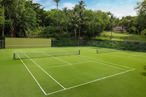 Green tennis courts sit among tropical trees at Sandals Regency La Toc.