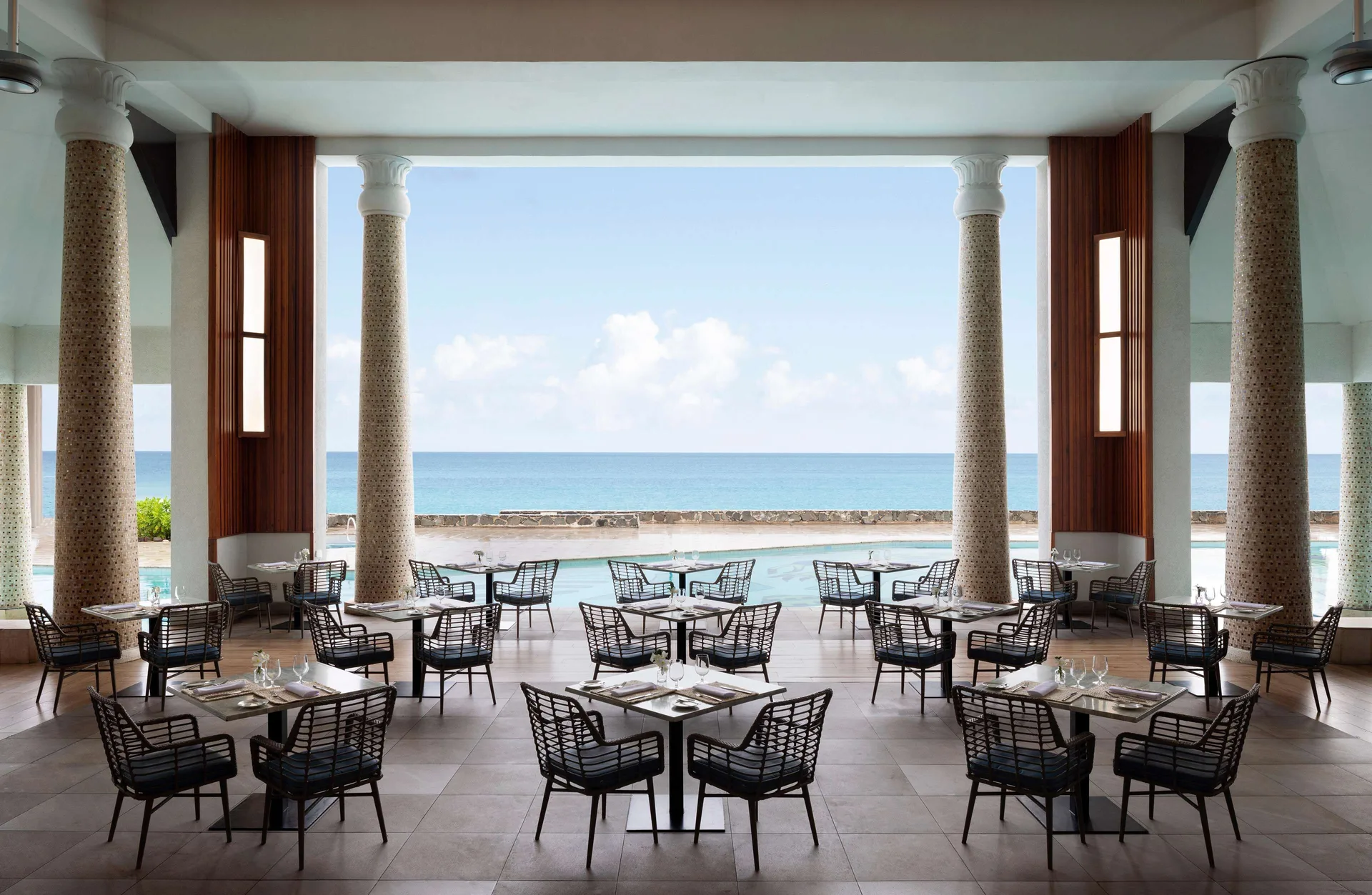 Open-air oceanview dining room with set tables at Sandals Regency La Toc.