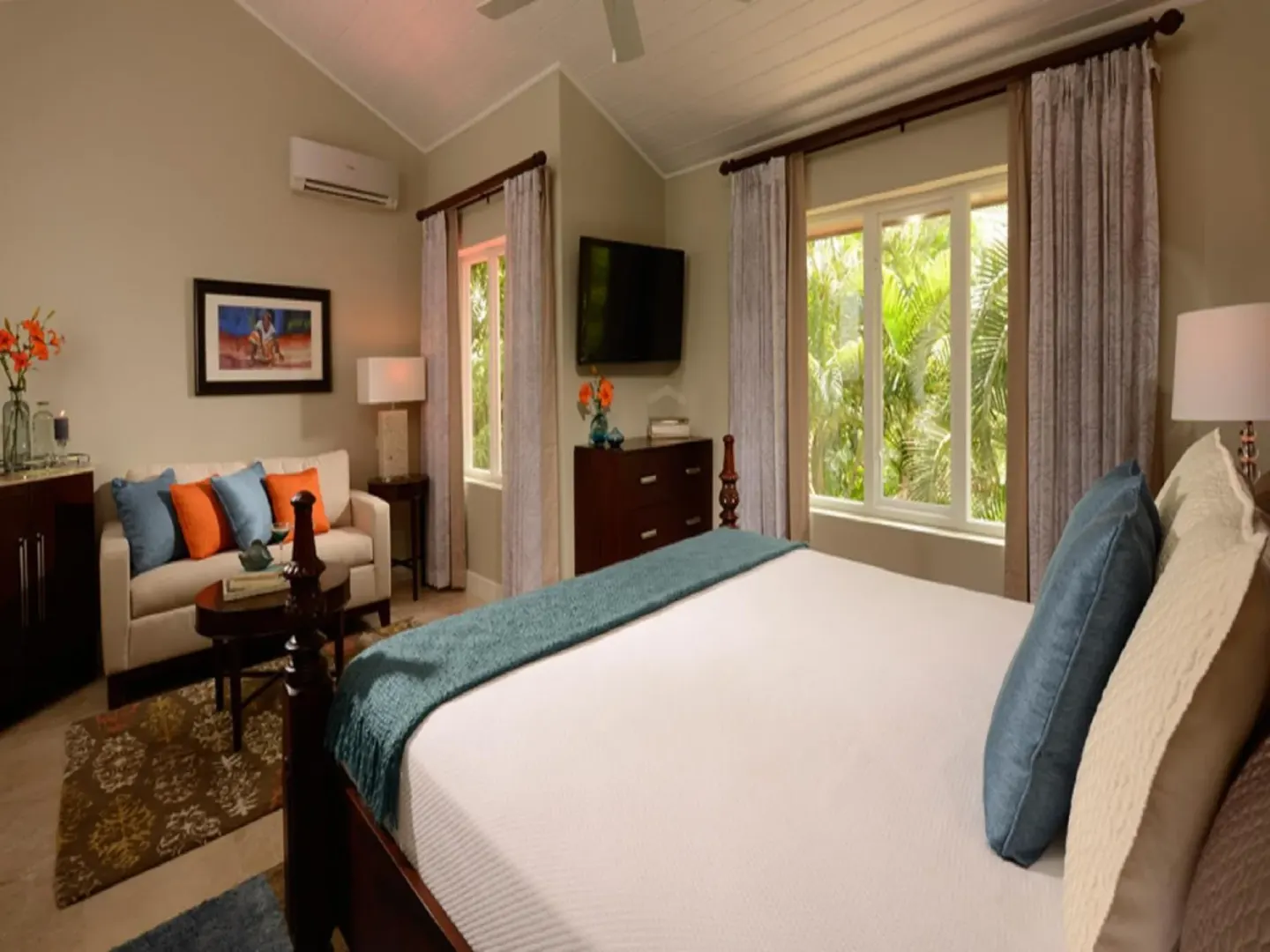 King bed, sofa and garden-facing windows in a guest room at Sandals Regency La Toc.