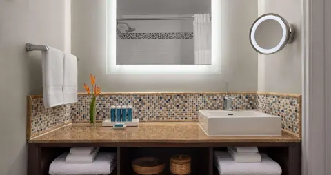 Honeymoon room bathroom vanity with vessel sink and lit mirror at Sandals Regency La Toc.