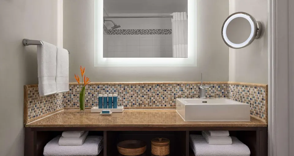 Honeymoon room bathroom vanity with vessel sink and lit mirror at Sandals Regency La Toc.