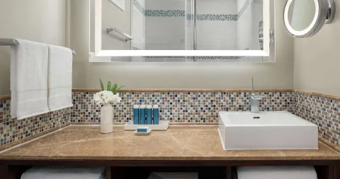 Bathroom vanity with mosaic tile and lit mirror at Sandals Regency La Toc.