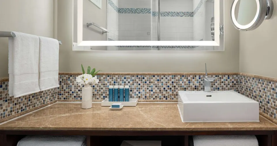 Bathroom vanity with mosaic tile and lit mirror at Sandals Regency La Toc.