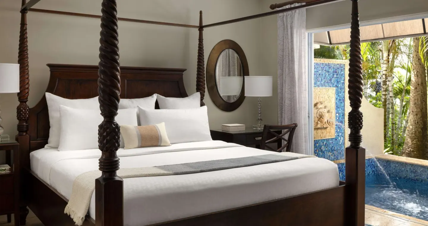 Four-poster king bed beside a private pool at Sandals Regency La Toc.