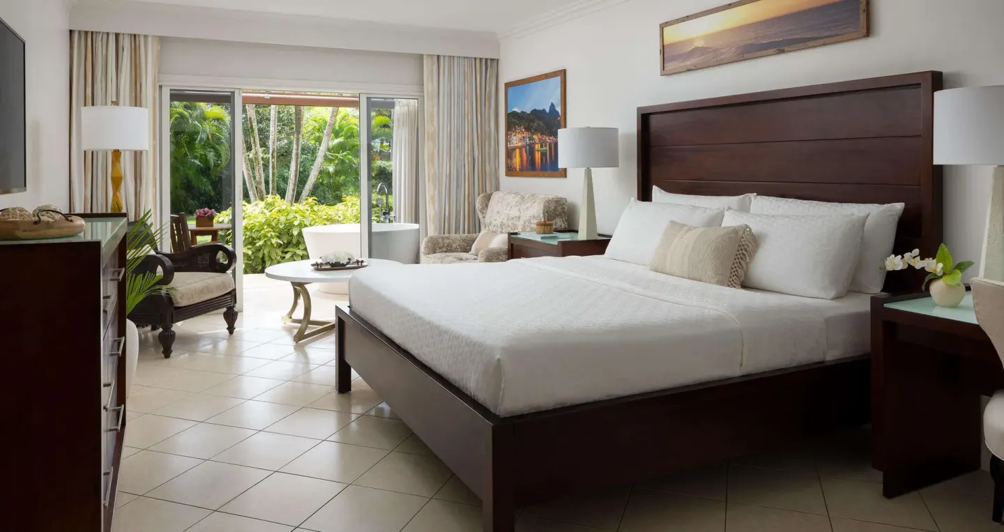 Honeymoon sanctuary junior suite king bed and garden patio at Sandals Regency La Toc.