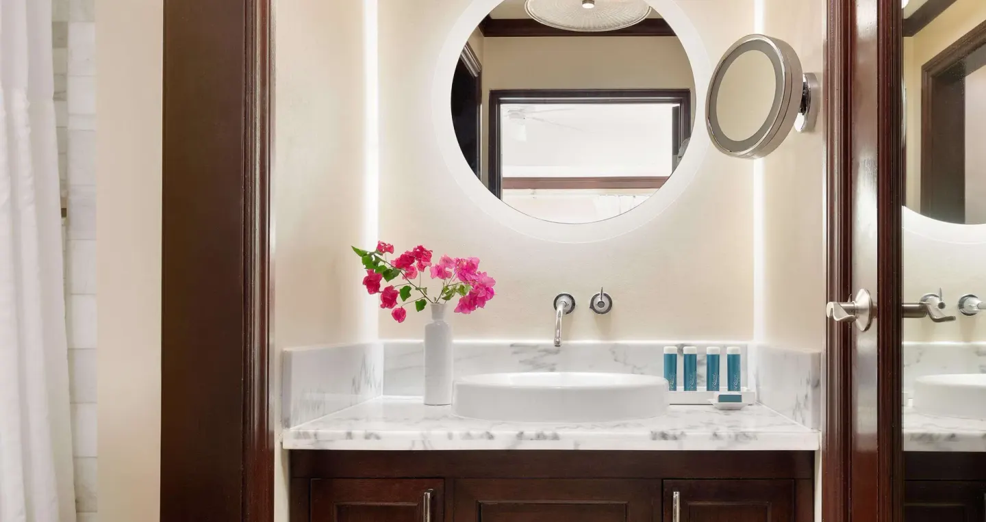 Bathroom vanity with round mirror in a luxury room at Sandals Regency La Toc.