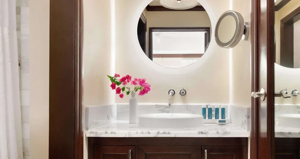Bathroom vanity with round mirror in a luxury room at Sandals Regency La Toc.