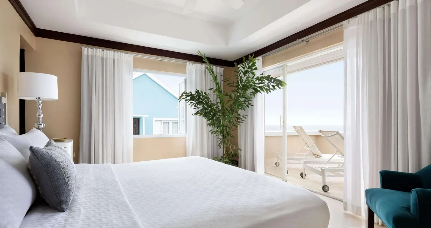 King bed and balcony doors in an ocean-view room at Sandals Regency La Toc.