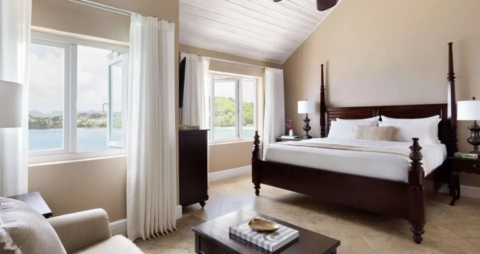 Four-poster bed and seating area with bay windows at Sandals Regency La Toc.