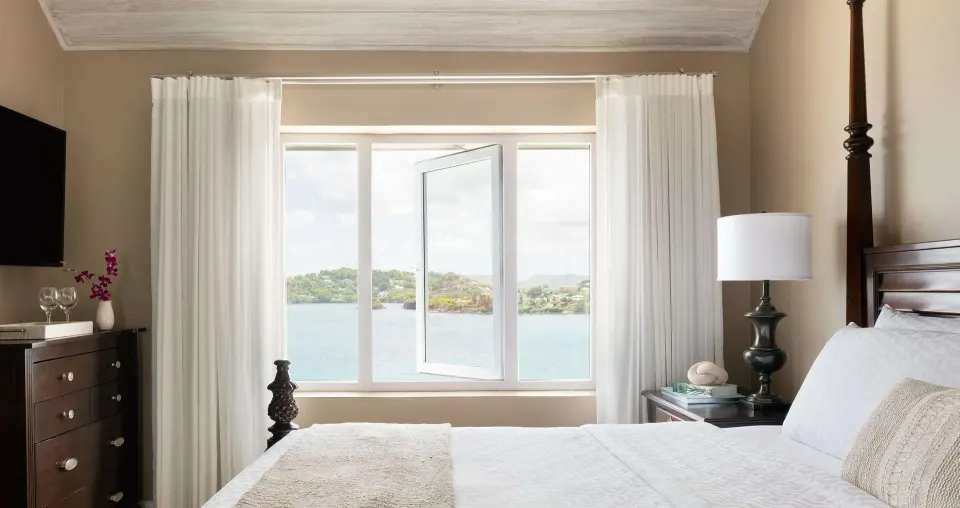 Ocean-view bedroom with four-poster bed at Sandals Regency La Toc.