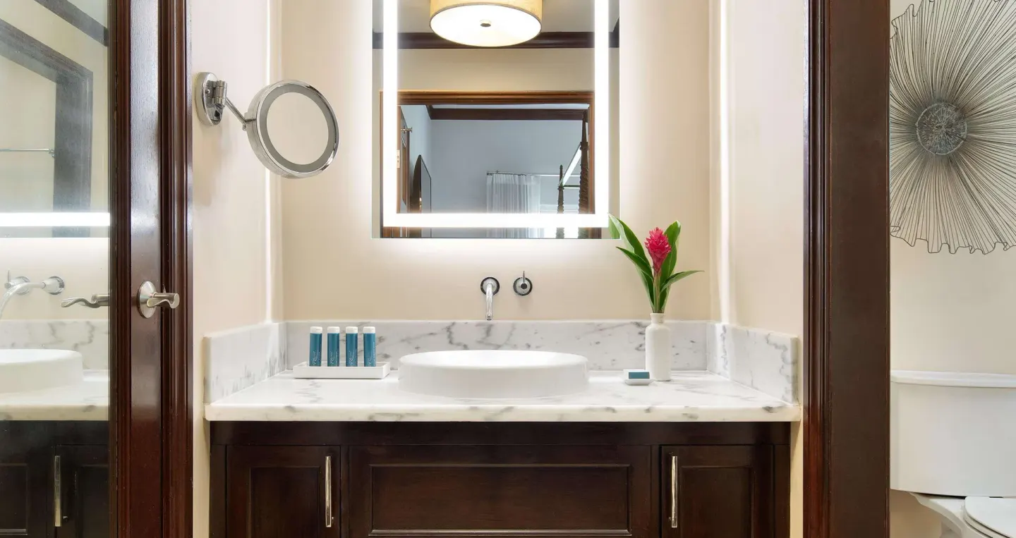Marble vanity and illuminated mirror in a suite bathroom at Sandals Regency La Toc.