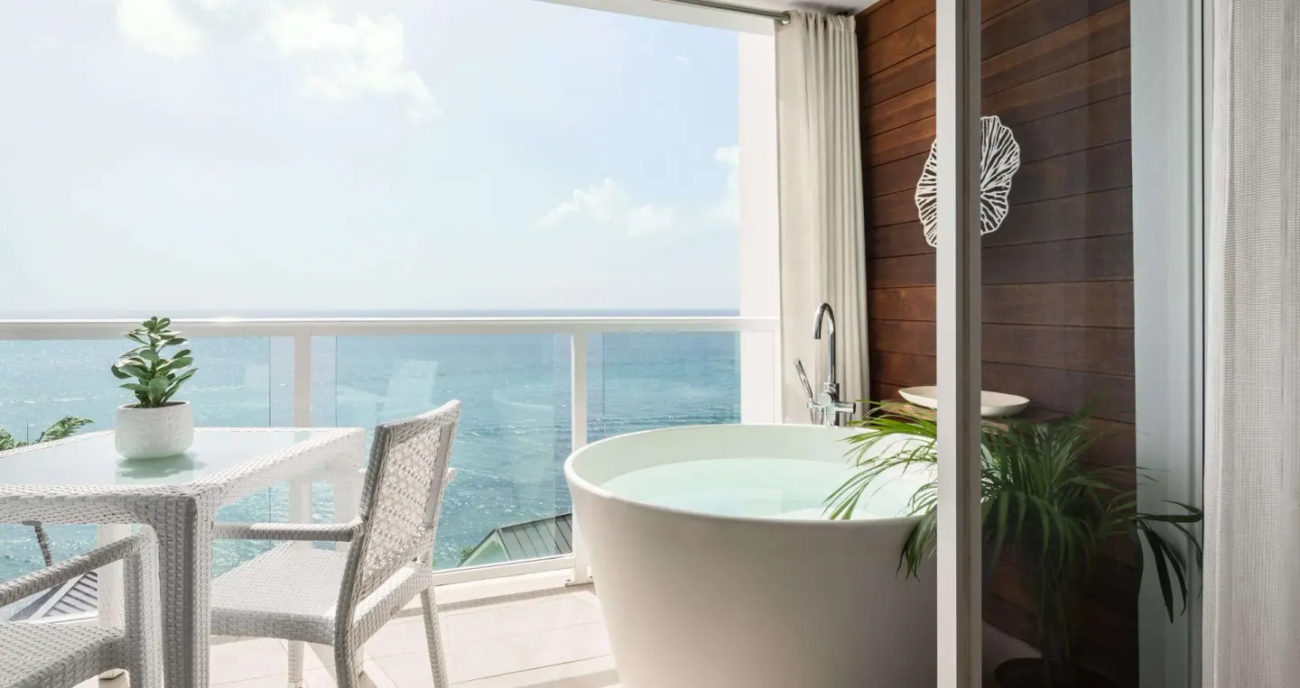 Ocean-view balcony with soaking tub and seating at Sandals Regency La Toc.