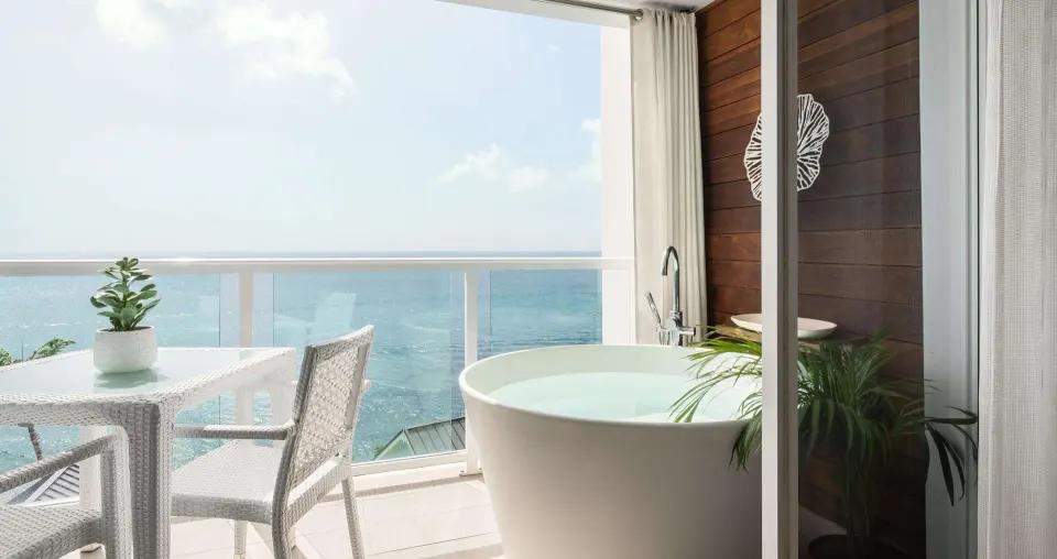 Ocean-view balcony with soaking tub and seating at Sandals Regency La Toc.