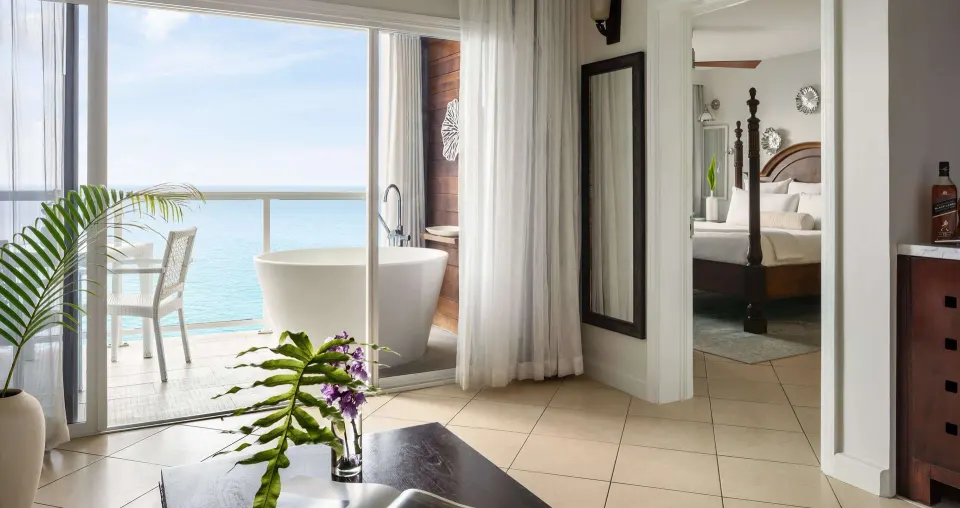 Balcony soaking tub and bedroom doorway in an ocean-view suite at Sandals Regency La Toc.