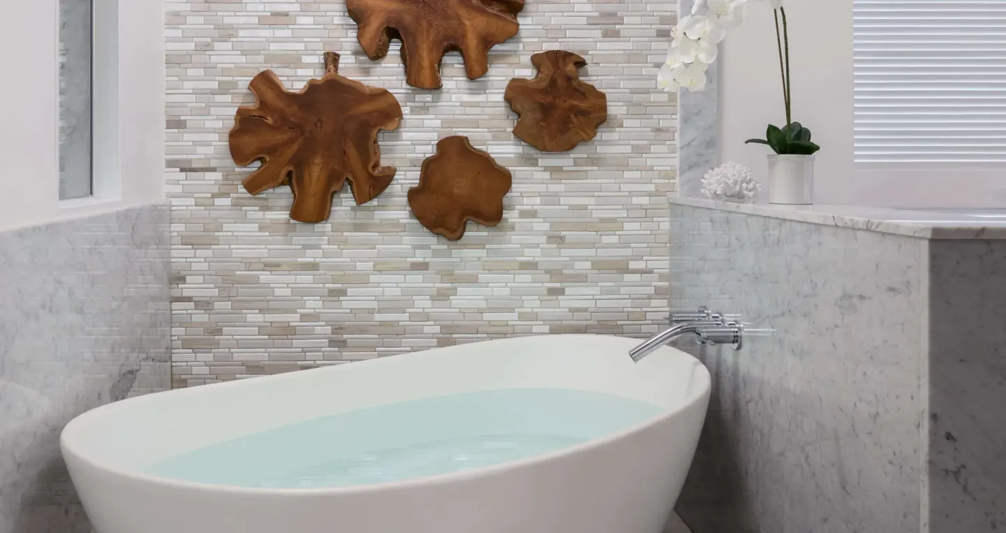 Freestanding bathtub with tile and wood wall art at Sandals Regency La Toc.