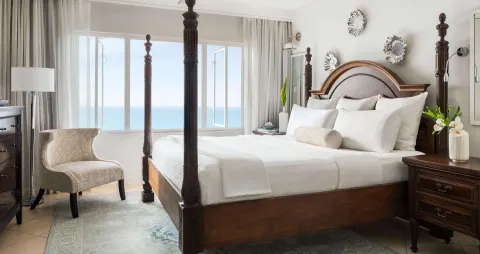 Four-poster king bed with ocean-facing windows at Sandals Regency La Toc.