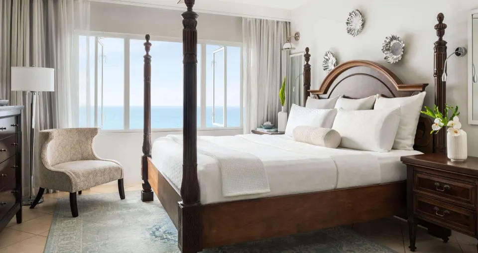 Four-poster king bed with ocean-facing windows at Sandals Regency La Toc.