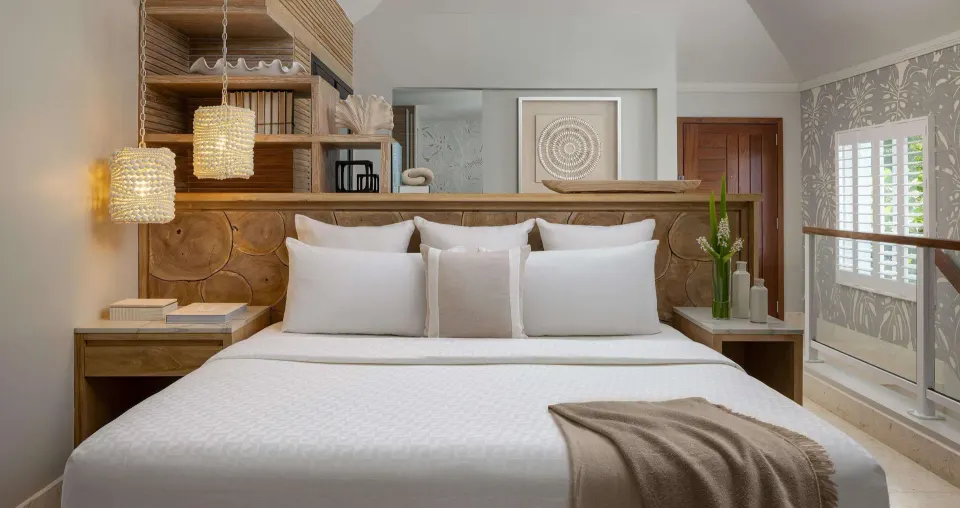 King bed with wood headboard in an oceanfront villa bedroom at Sandals Regency La Toc.