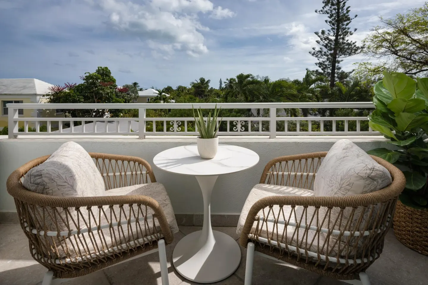 A balcony seating nook with two wicker chairs and a small table at Sandals Royal Bahamian.