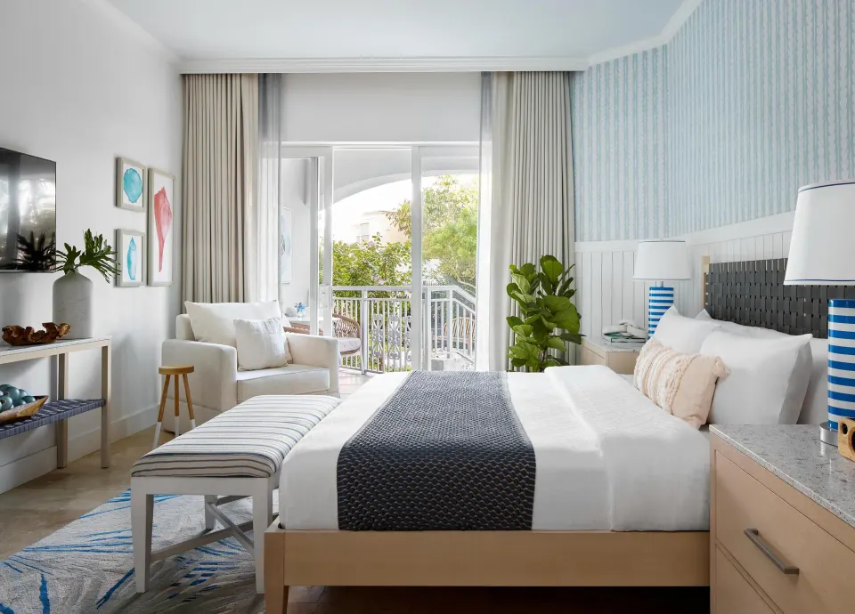 Bright king guest room with balcony seating at Sandals Royal Bahamian.