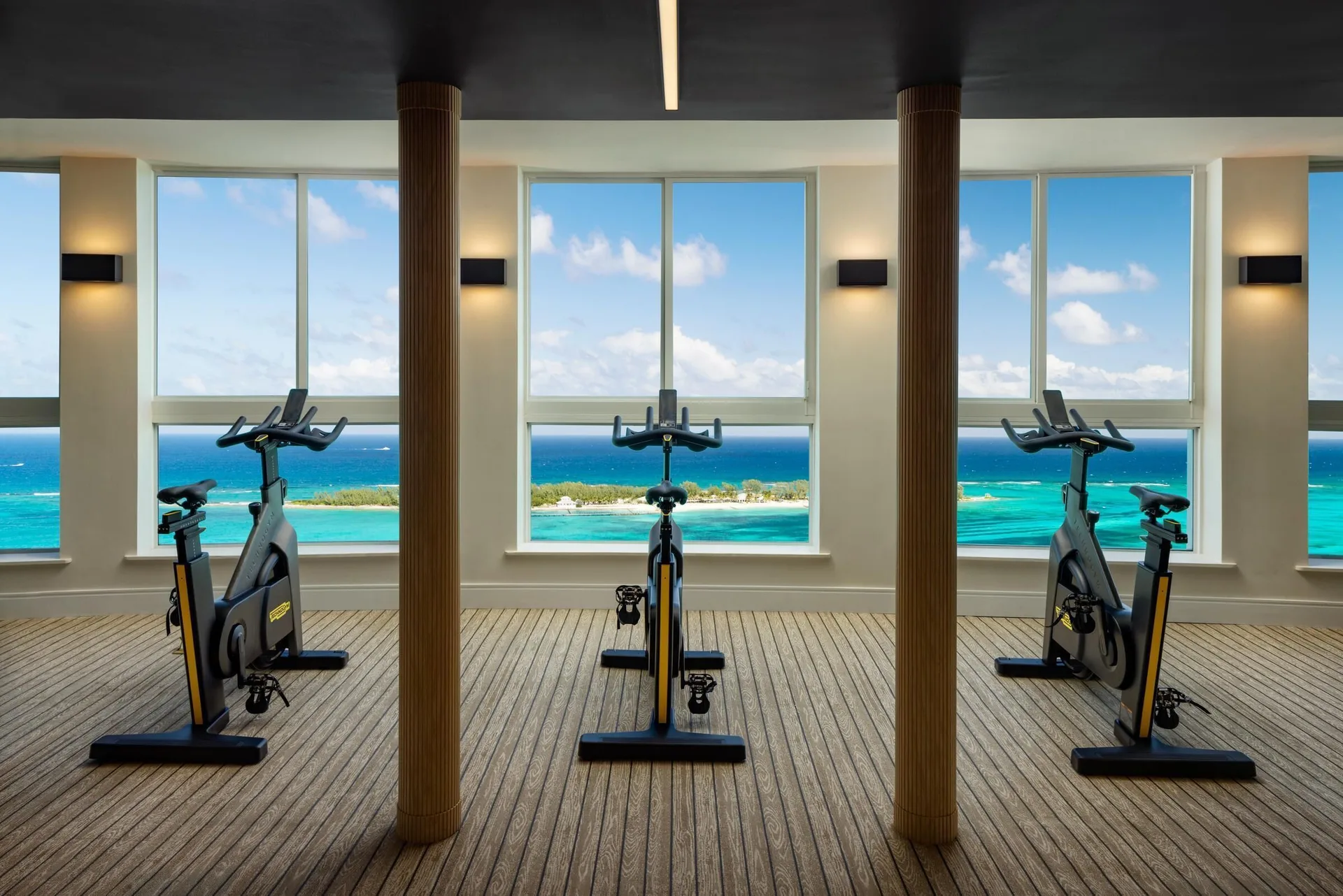 Exercise bikes facing ocean-view windows at Sandals Royal Bahamian.